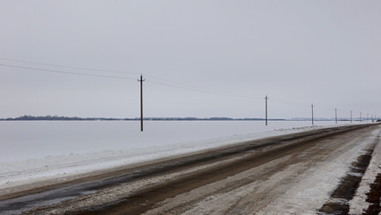 Fototapeta na wymiar Sad landscape with a deserted winter road in the steppe, Russia