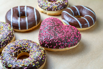 Mix donuts icing round shape and heart. Donuts strewed with decorative sprinkles top view