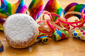 leckere frische Krapfen, Luftschlangen, Rotorspiralen, und Tröten auf Holz