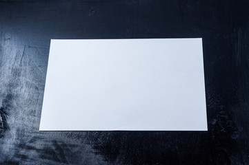 White sheet of paper against a painted black wood