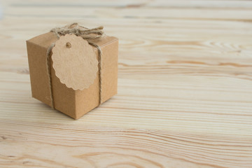 A box of natural color on a light wooden background with a label for signature. Place for text. View from above.