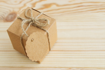 A box of natural color on a light wooden background with a label for signature. Place for text. View from above.