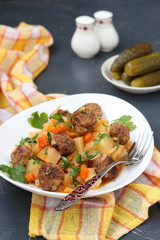 Stewed potatoes with meatballs on a white plate on dark background, Closeup, Vertical orientation