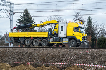 Fototapeta na wymiar Yellow machine crane servicing repair of railway tracks rides on rails