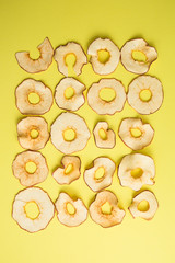 Apple chips on yellow background.Dried apple rings sprinkled with cinnamon on yellow background.healthy vegan snack,copy space