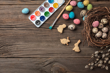 Colorful easter eggs and brushes on wooden table. Top view with copy space