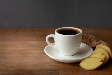 hot coffee in cup with ginger slice on old wood background