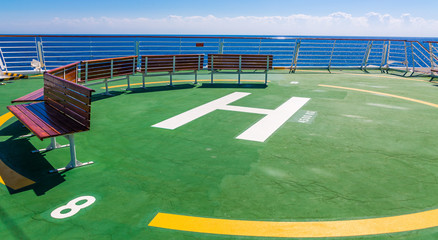 Obraz premium Benches on the green helicopter ship on the bow of a cruise ship