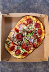Pizza with several toppings in delivery box