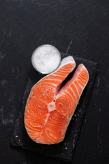raw salmon with salt on black ceramic background