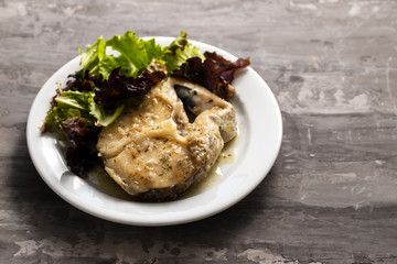 boiled fish with sauce and green salad on white plate