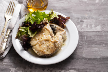 boiled fish with sauce and green salad on white plate