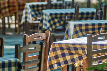 A group of tables and chairs in an outdoor restaurant in Greece
