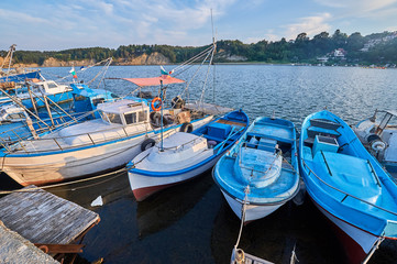 A series of small blue fishing boats moored in a harbor in a small Bulgarian town on the Black Sea