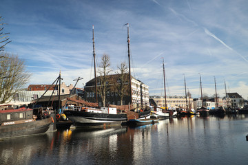 Fototapeta na wymiar old museum harbor of Gouda with historic ships at mallegatsluis sluice to the Hollandsche IJssel in the Netherlands