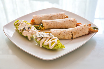 Burritos dish garnished with lettuce with roquefort cheese sauce