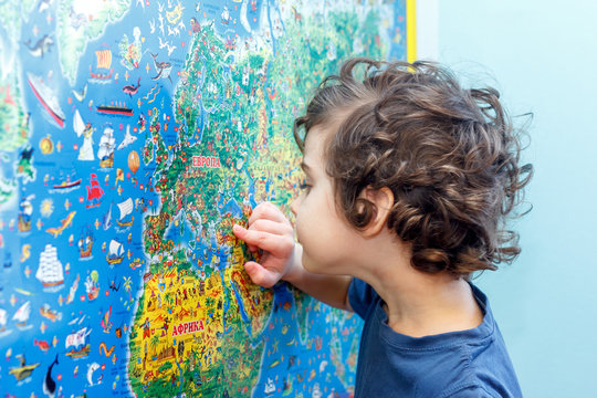 The curly-headed Child with interest looks at the blue world map