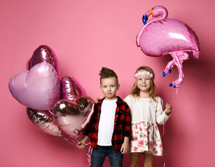 Cool little boy with color heart balloons and pretty little girl with flamingo balloon came...