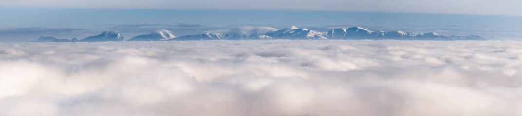 The peaks of the snowy mountains above the clouds