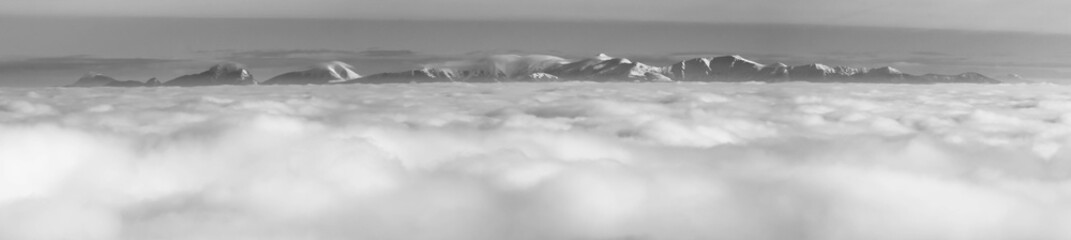 Fototapeta na wymiar The peaks of the snowy mountains above the clouds
