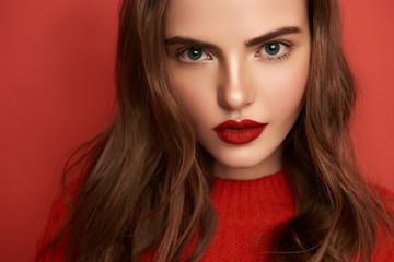 Attractive young lady with bright make up looking at camera indoors