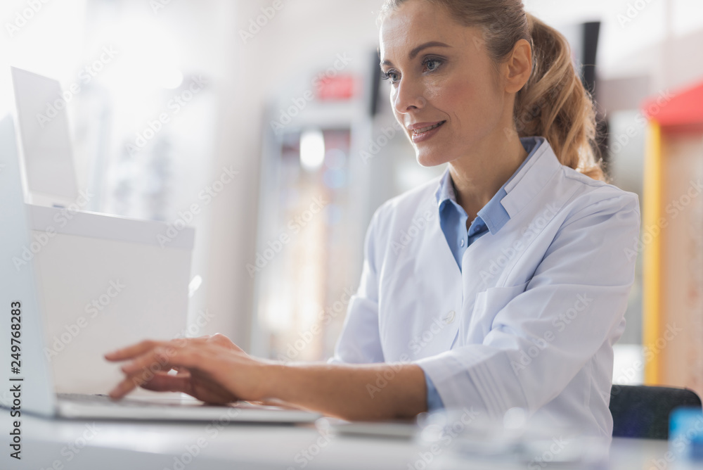 Poster Concentrated female optician using her laptop for work