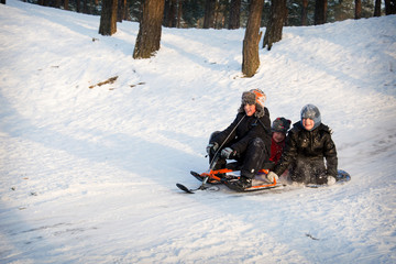 In winter, children ride a snow scooter from a hill.