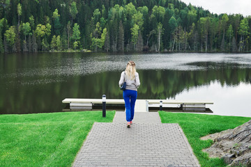 Young woman is having a rest in a picturesque place. She is moving the beautiful path towards the lake.