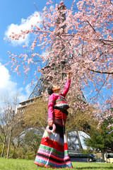 Femme de la tribu Taïlu sous le sakura en fleur avec la tour eiffel.