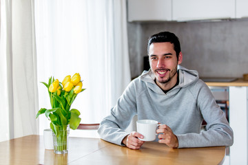 man sitting at table with cup of coffee or tea