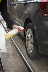 Man Spraying Car Soap for Washing a Car on Blurred Background
