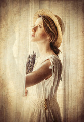 Woman in white dress holding lavender near window