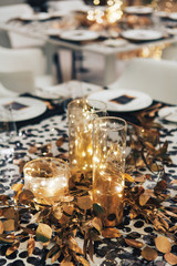 Fototapeta na wymiar Dinner tableis decorated in black and gold. Garland in a glass flask. Wedding decorations