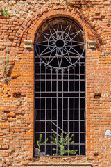 Arched window with bars of old abandoned red brick church