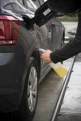 Man Spraying Car Soap for Washing a Car on Blurred Background