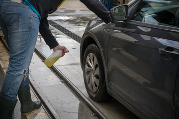 Man Spraying Car Soap for Washing a Car on Blurred Background