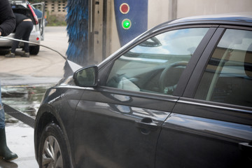 Man Using Water Pressure Machine to Wash a Car on Blurred Background