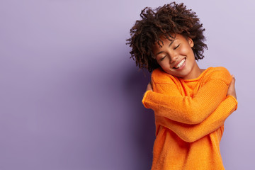 Photo of pleased dark skinned lady with Afro hairstyle, imagines meeting with boyfriend, embraces...