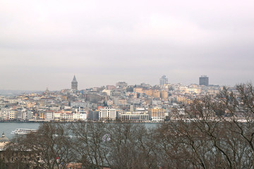 Fototapeta premium View of Istanbul through the Bosphorus and Golden Horn. Urban landscape with Galata Tower. Travel photography. Cloudy spring day.