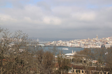 View of Istanbul through the Bosphorus and Golden Horn. Urban landscape with Galata Tower. Travel photography. Cloudy spring day.