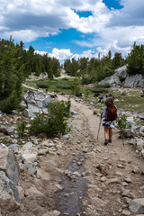 Female hiker concentrates while hiking on a dowhill slope in the Eastern Sierra Nevada mountains in the Little Lakes Valley trail