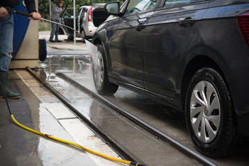 Man Using Water Pressure Machine to Wash a Car on Blurred Background