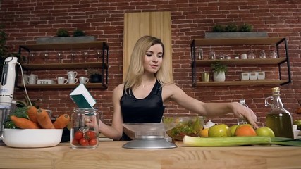 Beautiful fit woman with recipe in the cooking book checking all ingredients for vegetarian dish.