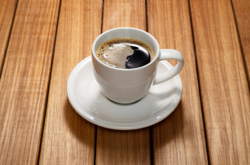 Close up photo of a coffee cup and saucer over a wood table