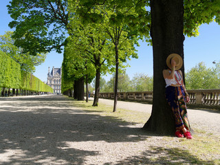 Femme à l'ombre d'un arbre dans une allée du jardin des tuileries à Paris