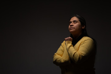 Hispanic Woman Deeply Gazing Away and Meditating on Dark Grey Background