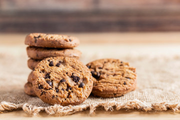 Chocolate chip cookies on sackcloth on wood table.  Copy space for your text or image.