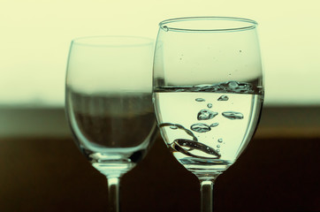 Wedding couple diamond rings falls in glass with water.