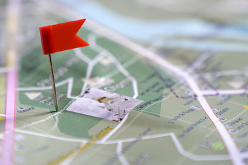 Travel concept: a red flag pinned to a landmark on a paper map