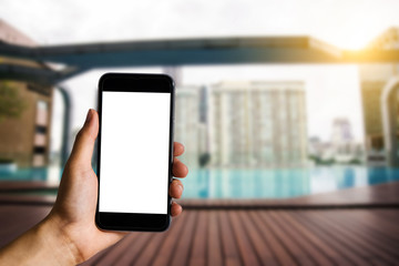 Hand holding white mobile phone with blank white screen  in the pool.